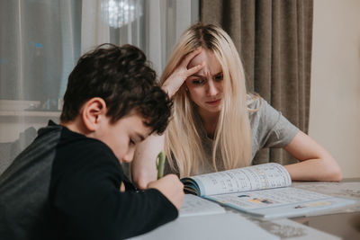 Mom and son are doing homework. sister helps brother solve math. home schooling. high quality photo