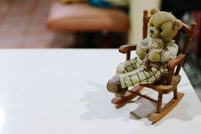 Close-up of teddy bear with small chair on table