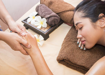 Cropped hand of person giving spa to woman on bed at home