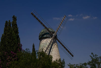 Low angle view of traditional windmill against blue sky