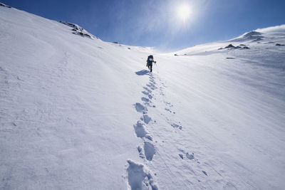 Female hiker aproaching summit of mengensdalstind in deep snow and high wind, moskenesøy, lofoten islands, norway