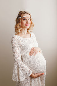 Portrait of pregnant woman standing against wall