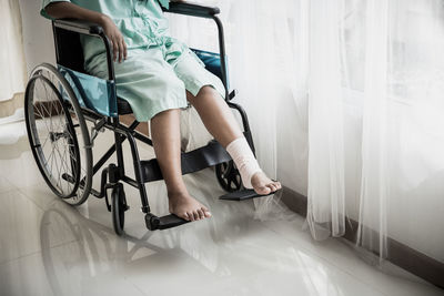 Low section of woman with bandaged leg sitting on wheelchair hospital