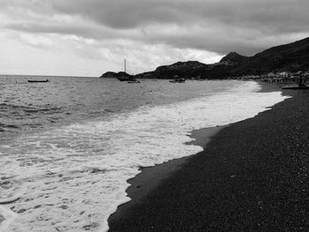 View of calm beach against cloudy sky