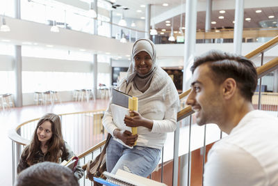 Smiling woman in hijab with friends on steps at university campus