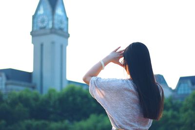 Rear view of woman shielding eyes against bell tower