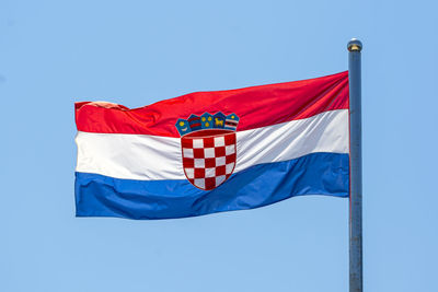 Low angle view of croatian flag waving against clear blue sky
