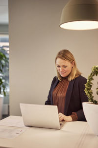 Smiling woman using laptop in office