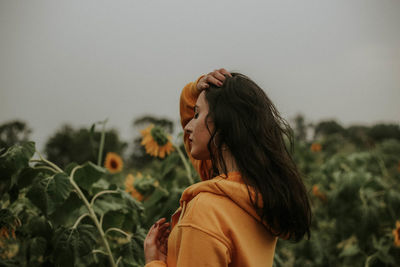 Side view of woman standing on field against sky