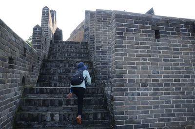 Rear view of woman walking on brick wall