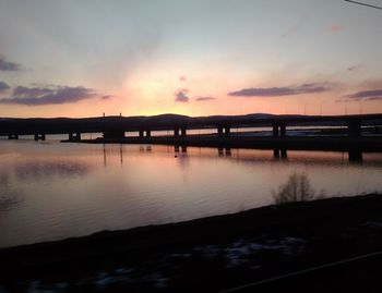 Silhouette bridge over lake against sky during sunset