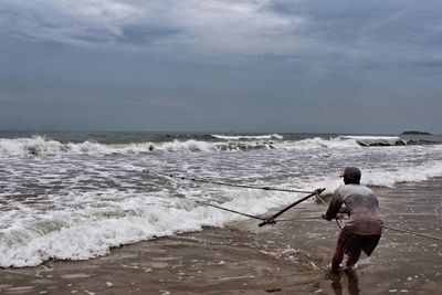 Rear view of man standing at beach