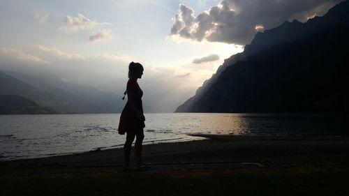 Silhouette woman standing against sea during sunset