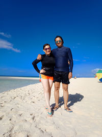 Full length of couple standing at beach on sunny day