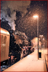 Illuminated city street against sky at night