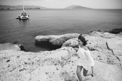 High angle view of cheerful teenage girl running on rocks against sea