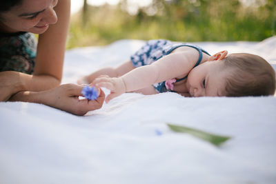 Mother playing with daughter on picnic blanket