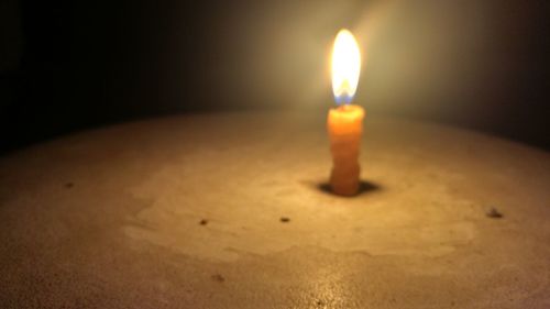 Close-up of lit candle in darkroom