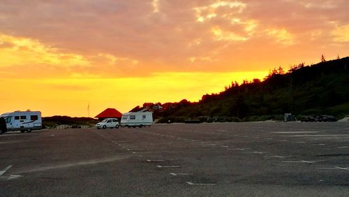 Houses by road against sky during sunset