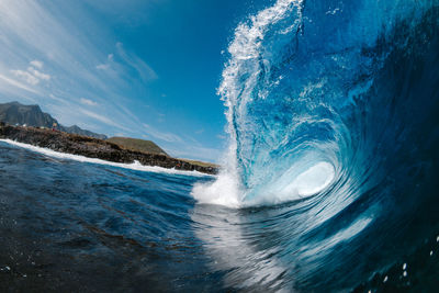 Water splashing in sea against blue sky