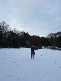 Man walking on snow covered landscape against sky