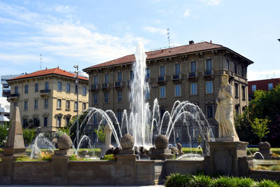 Fountain in city against sky