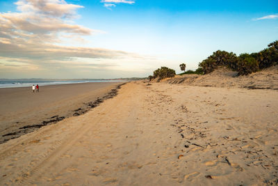 A man and a woman walking at shela beach at sunrise in lamu, unesco world heritage site in kenya