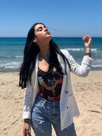 Young woman standing on beach against sea