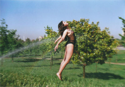 Side view of young woman on field against trees