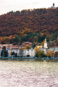 Houses by river against buildings in city