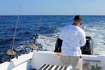 Rear view of man standing in sea against sky