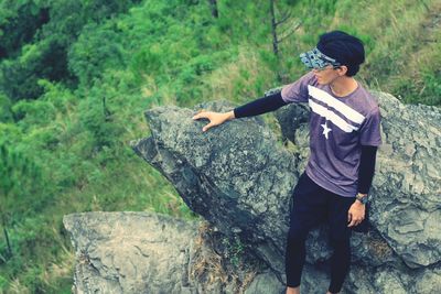 Full length of young woman standing on rock in forest