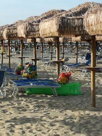 Deck chairs on beach against sky