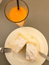 High angle view of cake in plate with orange juice on table