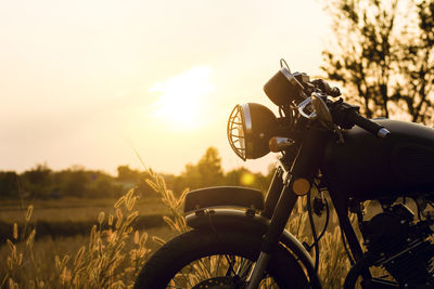 Close-up of bicycle on field against sky during sunset