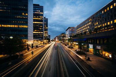 Illuminated road amidst buildings in city at night