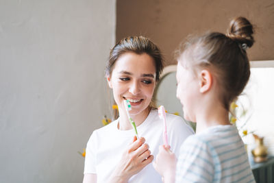 Young mother woman with little tween girl daughter in pajamas brushing their teeth at home