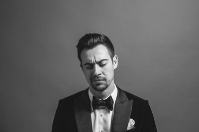 Portrait of young man standing against gray background