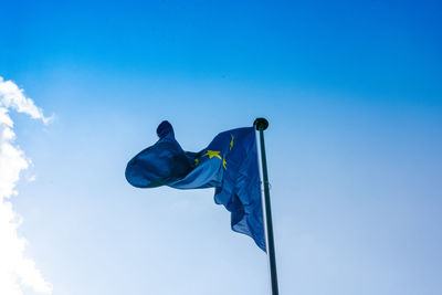 Low angle view of flags against clear blue sky