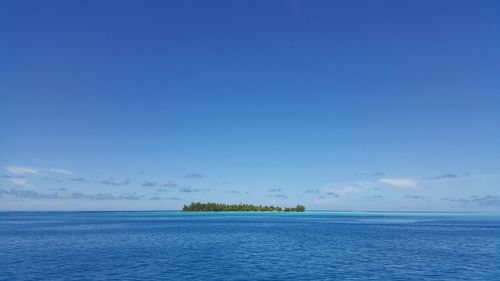 Scenic view of island in calm sea against sky