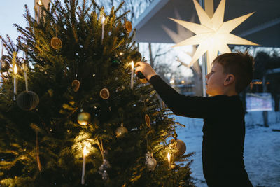 Boy decorating christmas tree at home