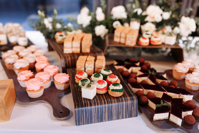 Candy bar decorated by delicious sweet buffet with cupcakes, eclairs, sweetness and flowers,