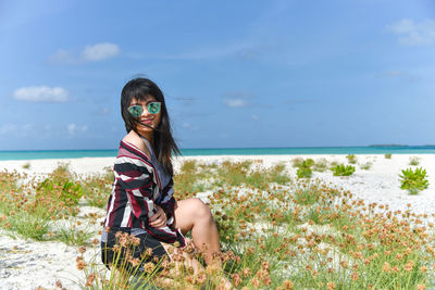 Portrait of young woman sitting at beach