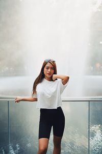 Portrait of smiling young woman standing against fountain