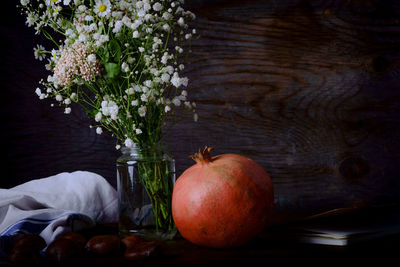 Close-up of pomegranate by flowers on table