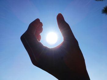 Low angle view of hand against bright sun