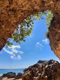 Low angle view of rock formation by sea against blue sky