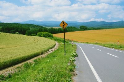 Road amidst field against sky