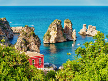 Panoramic view of rocks and sea against blue sky