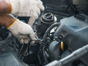 Midsection of man repairing car engine